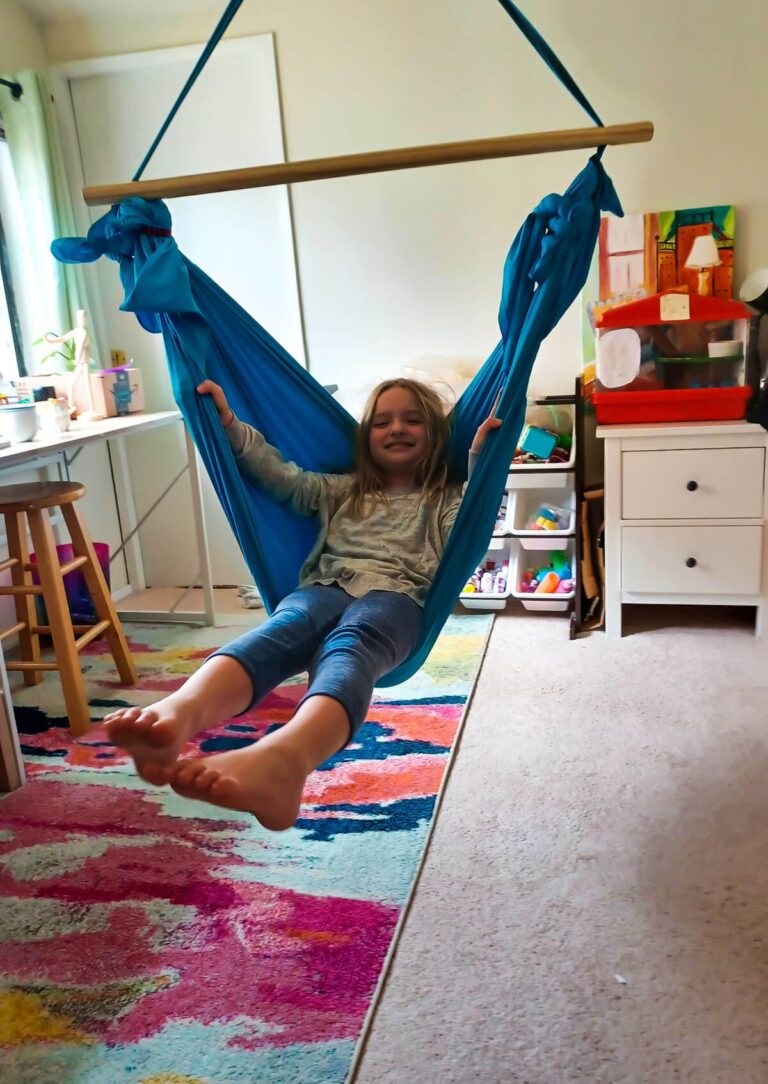 Child engaging in heavy work by pushing against the resistance of a stretchy therapy swing.